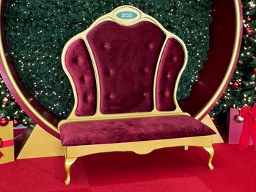 A plush red and gold throne chair with a 2025 emblem.