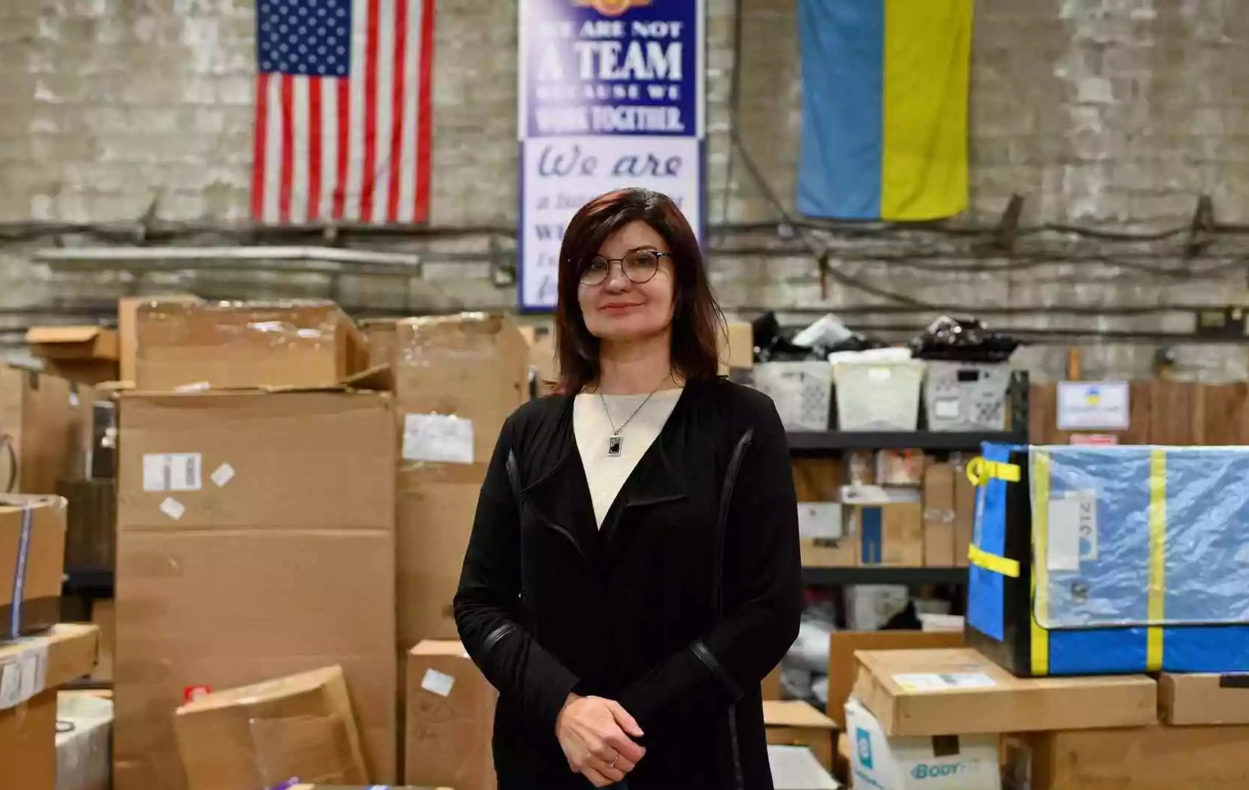 Woman in dark suit standing in front of shipping boxes