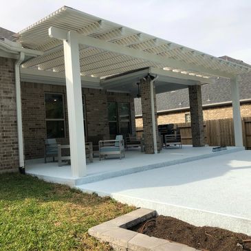 White aluminum pergola attached to back patio of brick home post on concrete slab. 