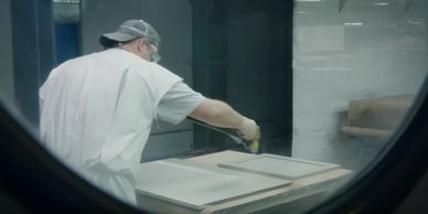 Specialty cabinet painters spraying opaque stain on cabinet doors in a dust proof environment. 