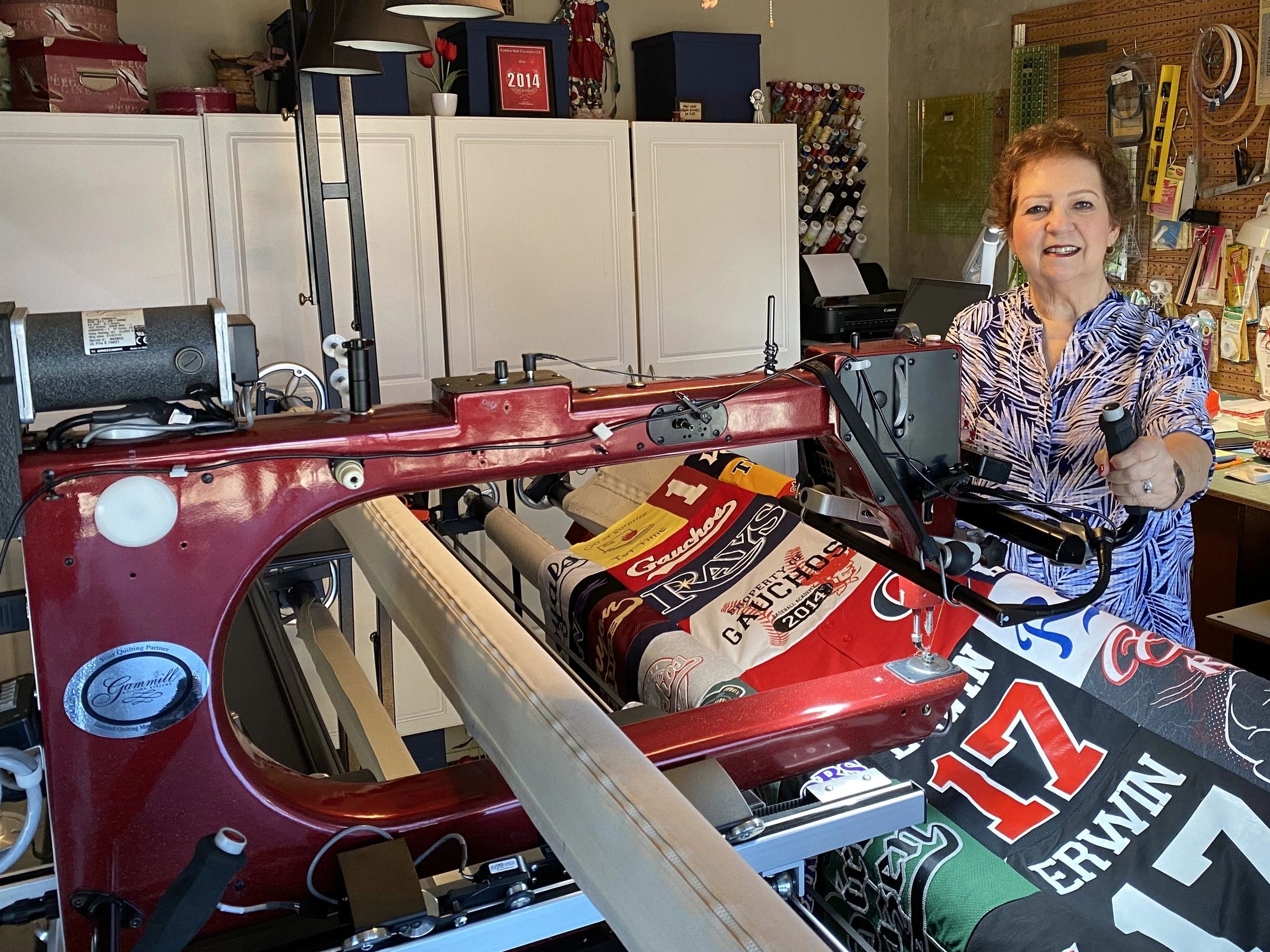 A woman smiling and holding a sewing machine 