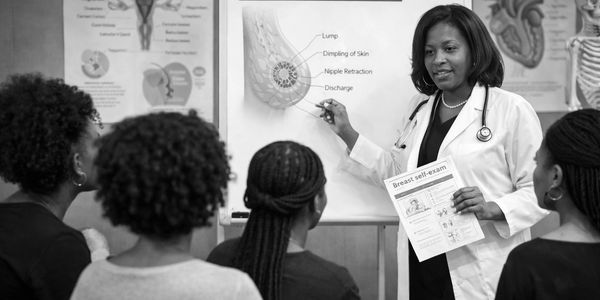 Doctor educates women on breast self-exam using a visual aid and pamphlet.