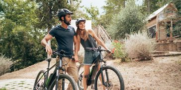 Couple with bicycles holding hands outdoors.