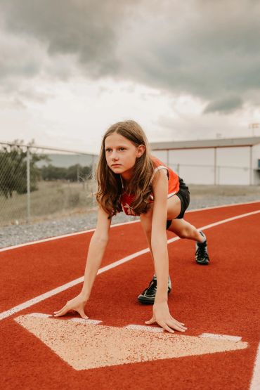 Young girl in starting position on a running track ready to race.