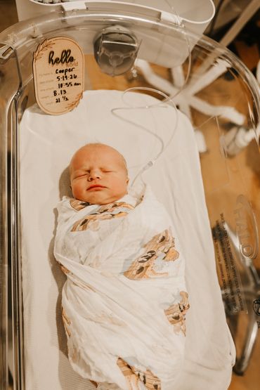 Newborn baby named Cooper sleeping in a hospital bassinet.