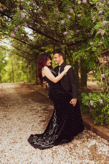 Couple in elegant evening attire shares a romantic moment outdoors.
