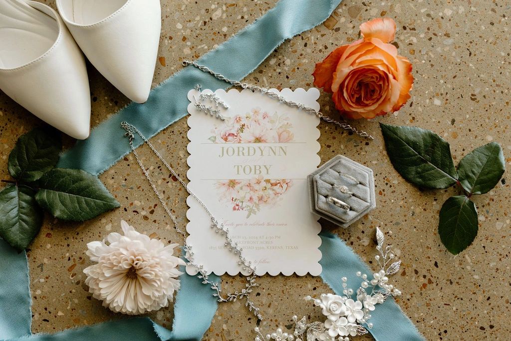 Flat lay of wedding day rings, jewelry and invitation for a wedding venue in Corsicana, Texas.