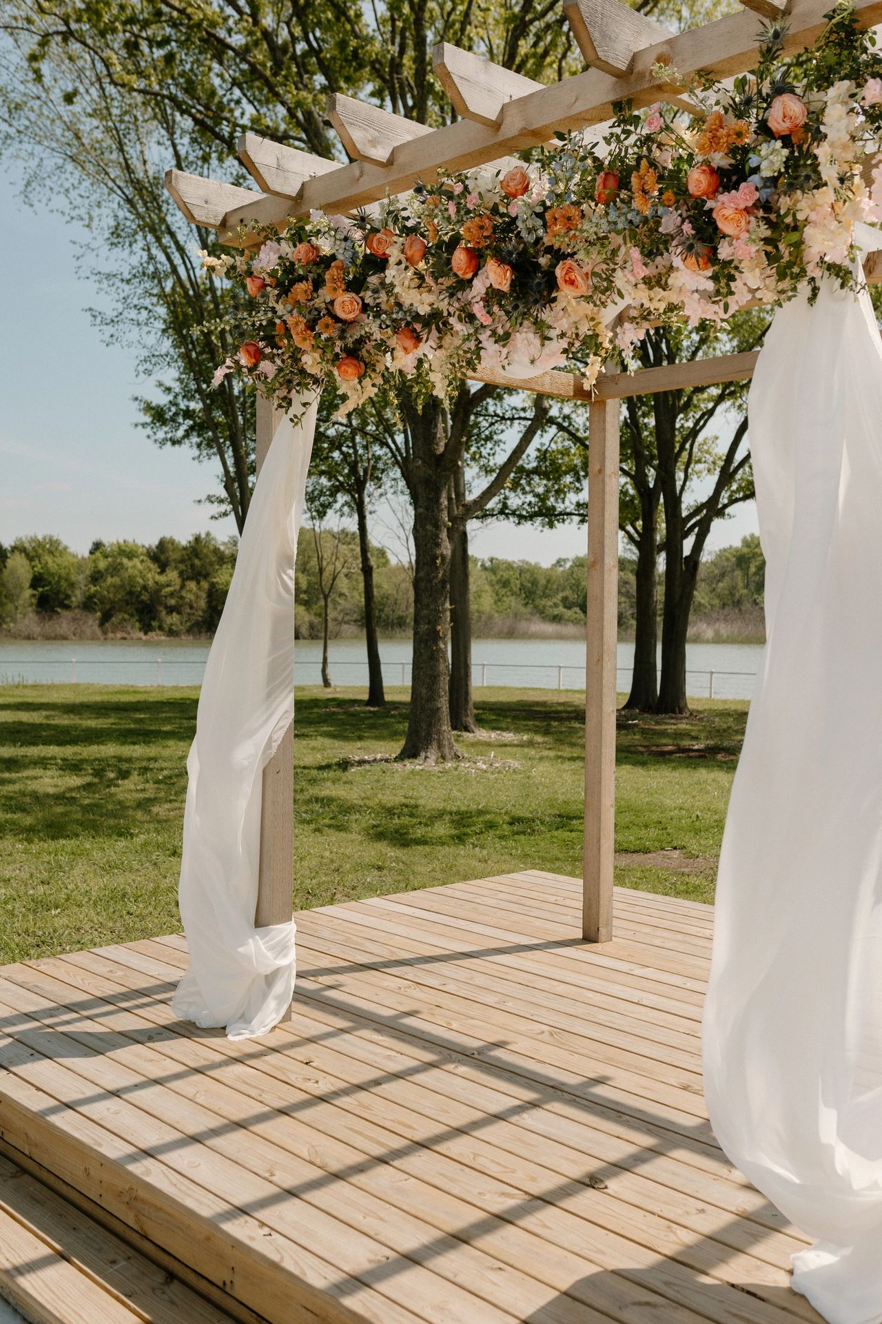East Texas wedding venue with lake backdrop. Wedding arch with peach and cream flowers.