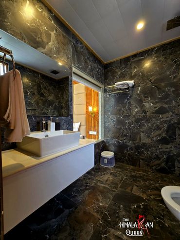 Modern bathroom with dark marble walls and white fixtures.