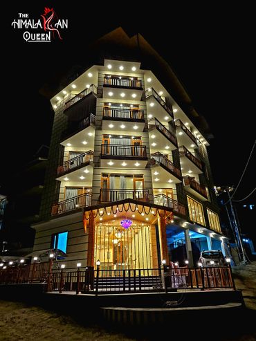 Night view of a brightly lit multi-story building with balconies and decorative lights.