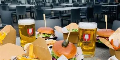 Burgers, fries, and beers set on a table in an outdoor dining area.