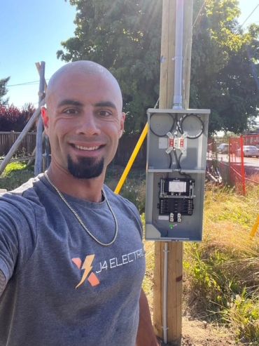 Man taking selfie near an open electrical panel outdoors.