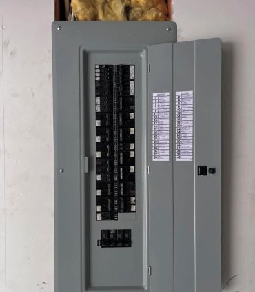 Open electrical breaker panel with labels on the door.