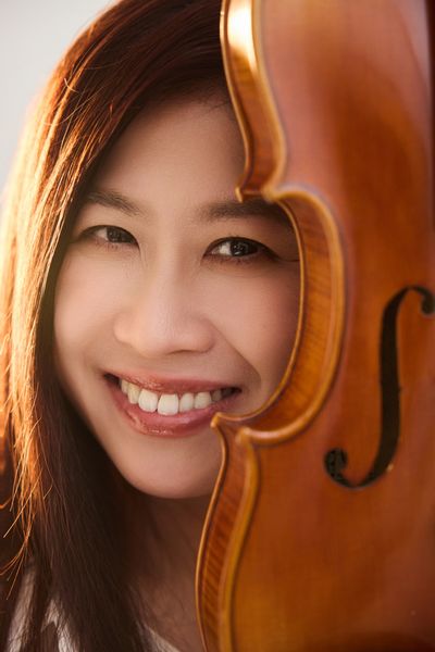 Woman smiling behind a violin.