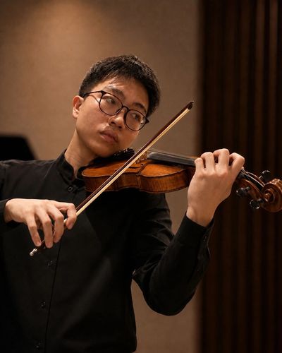 Young man playing the violin with focus and passion indoors.