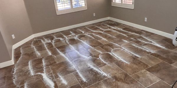 Brown tiled floor with white powder marks in empty room.