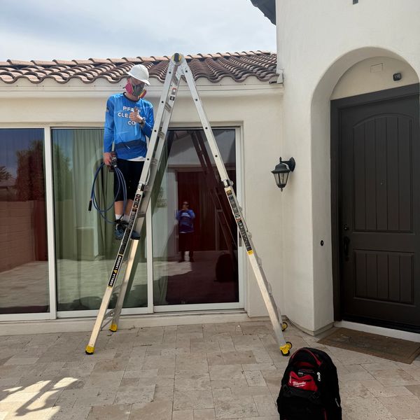 Man standing on a ladder outside a house.
