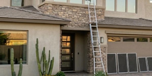 Modern home entrance with desert landscaping and a ladder on the garage.