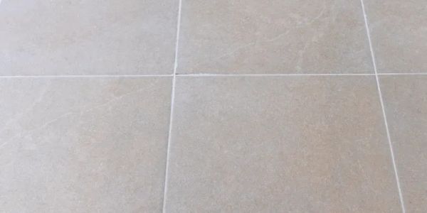 Close-up of beige tiled floor with grout lines.