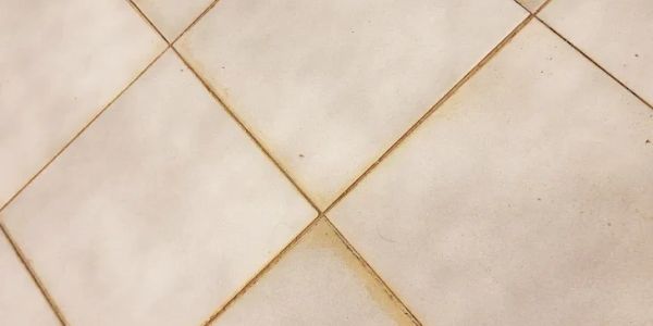 Close-up of dirty tiled floor with grout discoloration.