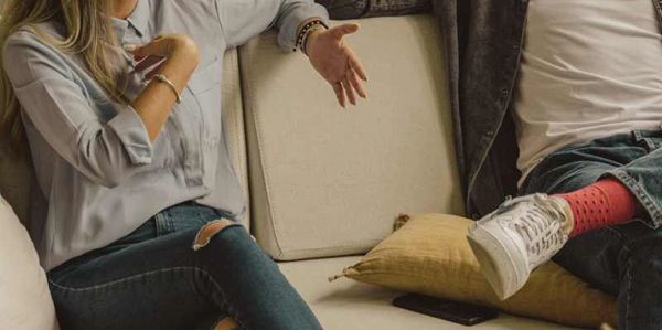 Couple sitting on a couch during a therapy session while engaged in an emotional discussion.
