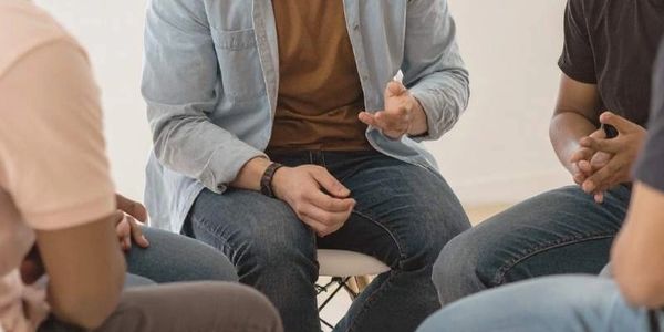 Closeup of three men’s hands during a men’s group session focused on support and connection.