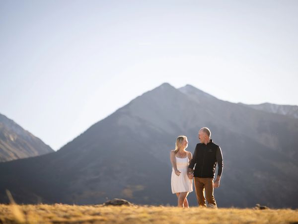Couple holding hands in a mountain landscape at sunset.