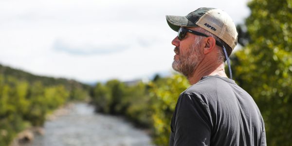 J. Bary Morgan of Fire Poppy Coaching looking out over a rushing river surrounded by lush green tree