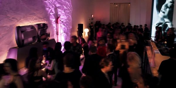 Crowd at a dimly lit party or club with purple lighting.