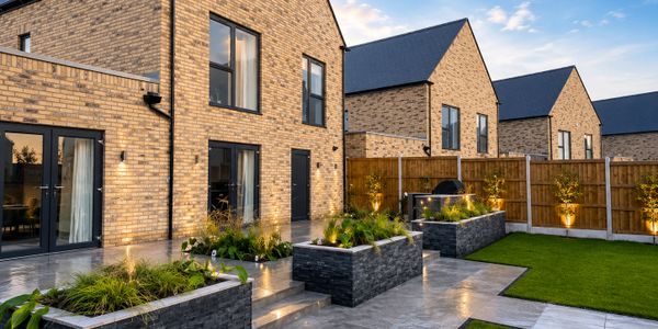 Modern brick houses with landscaped gardens and outdoor lighting at dusk.