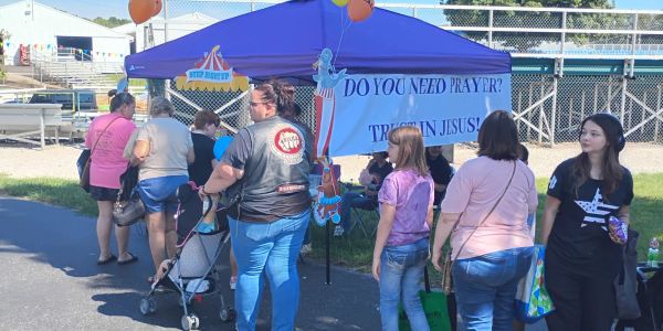 People gather near a prayer tent offering spiritual support in Jesus.
