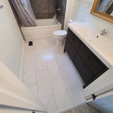 Tiled bathroom renovation with marble floors and new vanity.