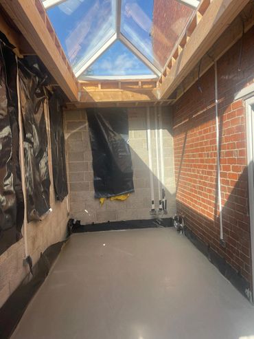 Room under construction with a glass roof and brick walls.