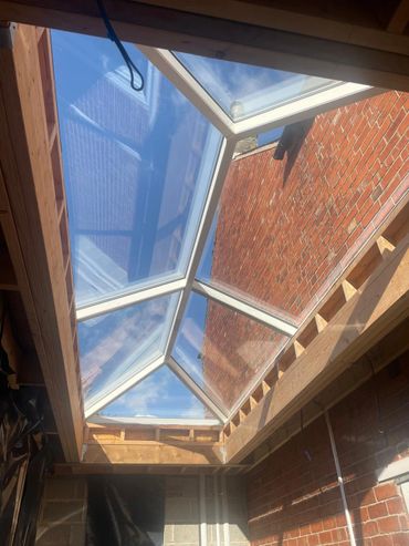 Newly installed glass roof with wooden framing and brick walls.