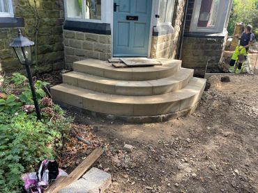 Newly constructed stone steps leading to a blue front door of a house.