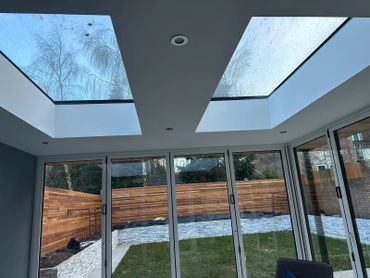 Modern room with large skylights and glass doors overlooking a garden.