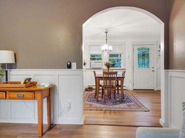 Cozy dining area with wooden furniture and a decorative rug under a bright chandelier.