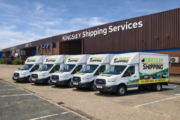 Fleet of Kingsley Shipping delivery vans parked outside the company warehouse.