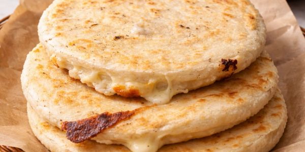 Two cheese-filled pupusas stacked on parchment paper.