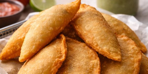 Golden fried empanadas stacked together.
