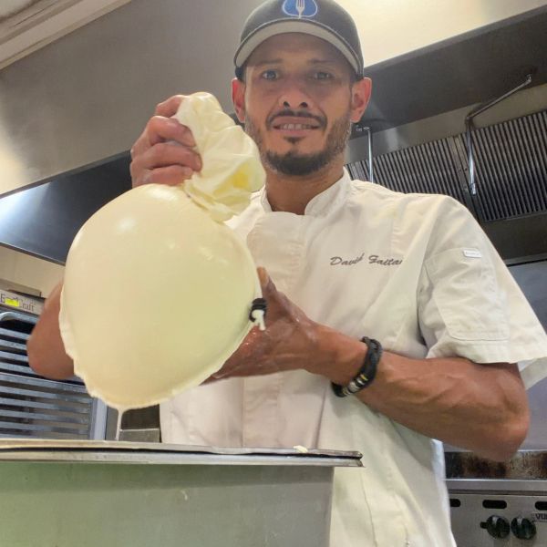 Chef inflating a large balloon with cream or batter.
