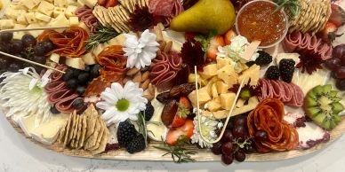 Assorted charcuterie board with fruits, cheeses, and crackers.