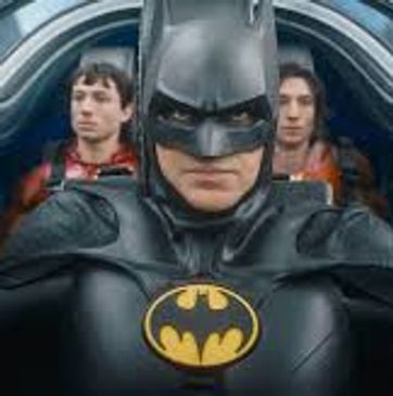 Batman in costume with two people behind him.