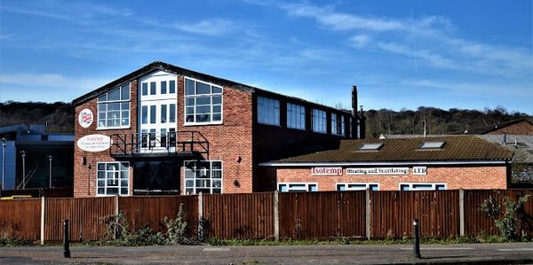 Brick industrial building with clear blue sky and wooden fence.