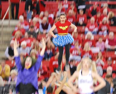 Cheerleader lifted high in a crowded stadium.