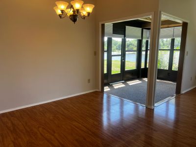 Empty room with chandelier and view of lake through glass door.
