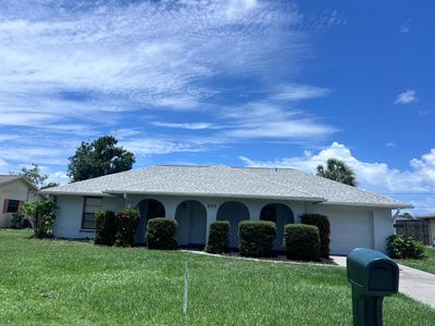 Single-story house with green lawn and blue sky.
