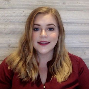 Young woman with blonde hair and maroon blouse smiling at the camera.