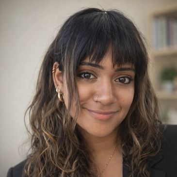 Smiling woman with curly hair and a nose ring wearing a black blazer.