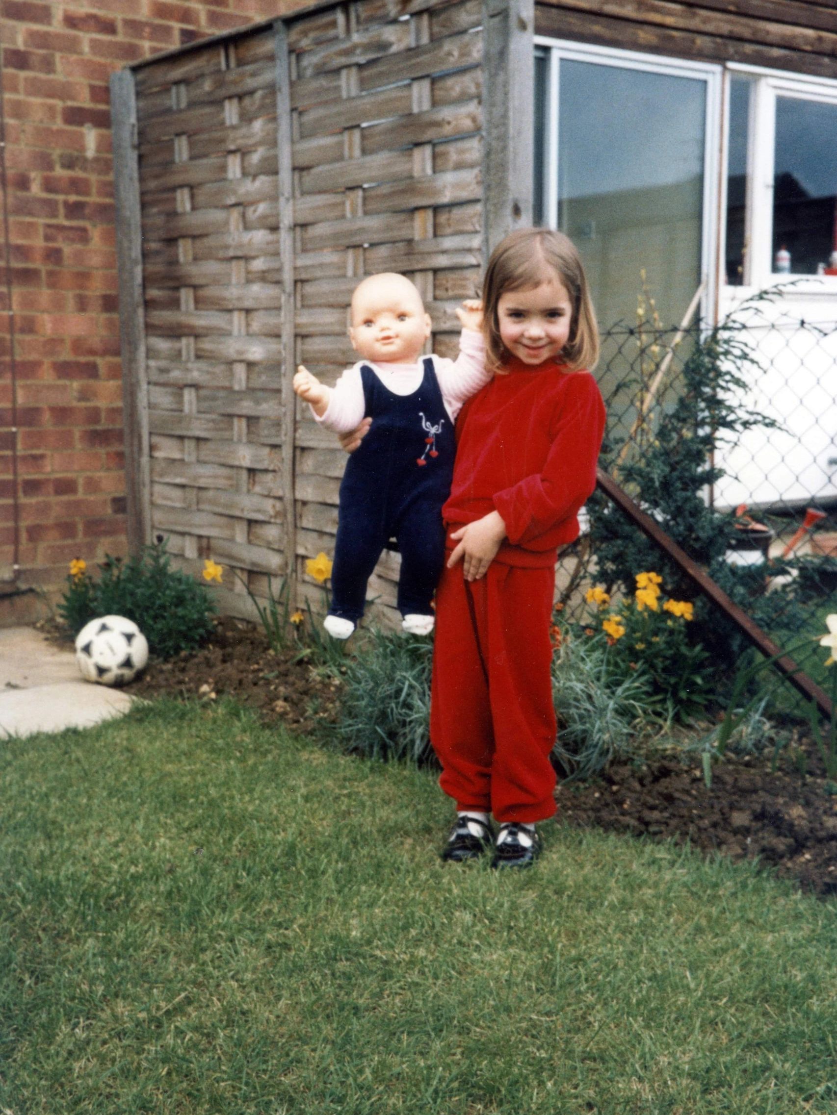 Young girl holding a large doll.